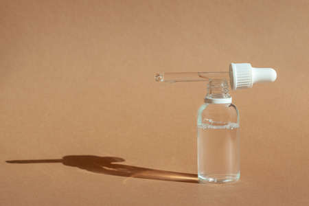 Cosmetic dropper bottle for serum, micellar toner and emulsion on brown background. Skin care,...