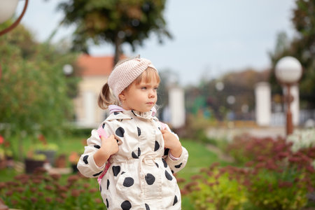 Little child with backpack looking away in autumn park.の写真素材