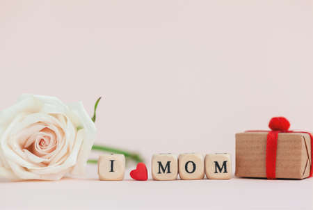 Happy Mother's Day. Beautiful rose flower and gift box with text i love mom on pink background. Greeting card for holiday concept.の写真素材