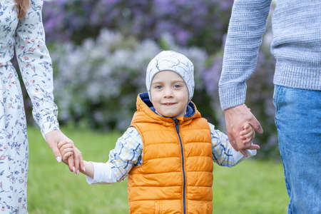 Son holding mother and father for hands. Happy family walking in the summer park and holding hands.の写真素材