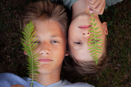 Close up portrait of two kids looking at the camera in asummer evening lying on green grass