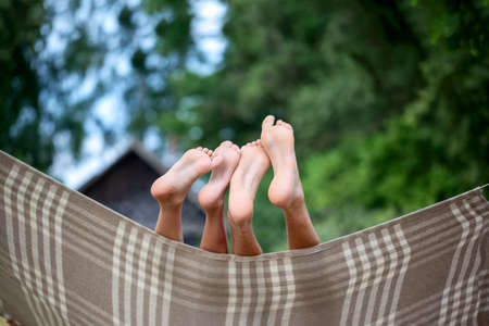 Two brothers kids relaxing in hammock at countryside in summer day. Child legs on hammock at nature background. Rest conceptの写真素材