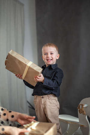 Little smiling Boy holding gift box isolated on dark wallpaper. Holiday festive conceptの写真素材