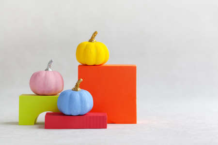 Colorful pumpkins on colourful podiums or pedestals over white background. Holiday Halloween party concept.の写真素材