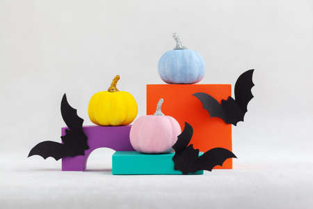 Colorful pumpkins on colourful podiums or pedestals with buts over white background. Holiday Halloween party concept.の写真素材