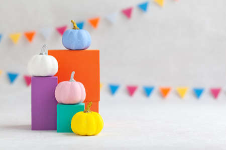 Colorful pumpkins on colourful podiums or pedestals over white background. Holiday Halloween party concept.の写真素材
