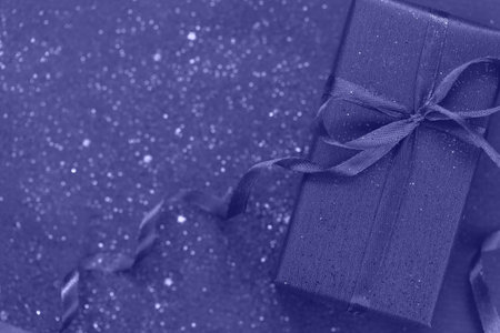 Trendy Color of Year 2022 Very Peri. Purpule gift box with bow on trendy color background with little sparkles. Flat lay style. Holiday concept.の写真素材