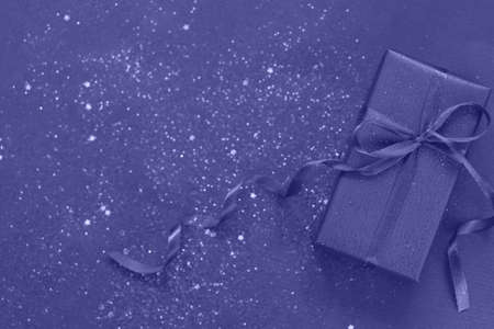 Trendy Color of Year 2022 Very Peri. Purpule gift box with bow on trendy color background with little sparkles. Flat lay style. Holiday concept.の写真素材