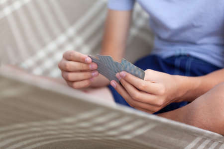 Close-up of a child's hands holding playing cards. board games outdoorsの写真素材