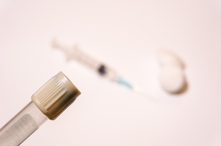 Blood tube with blurry background of syringe and cotton ballの写真素材