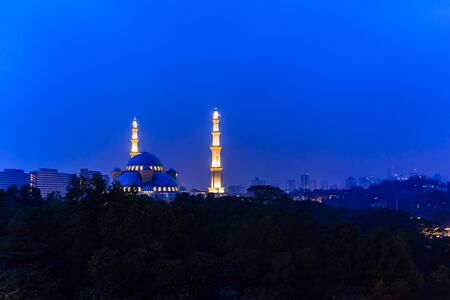 sunrise over silhouette mosque and hazy Kuala Lumpur city skyline