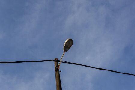 closeup view of a street lamp turned off by day over blue sky