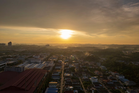 Golden hour illuminates the city, casting a warm glow over rooftops and streets below.の写真素材