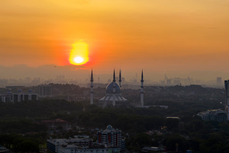 The mosque stands tall against the backdrop of a city awakening at sunrise.の写真素材
