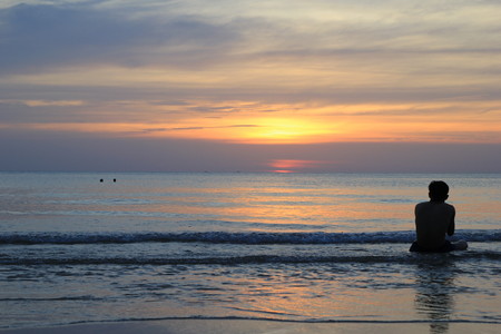 Travel to island Koh Chang, Thailand. The sitting man on the beach on the colorful sunset.の写真素材