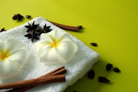 White towel with flowers of plumeria with stars of anise and cinnamon sticks on the yellow background for spa theme.の写真素材