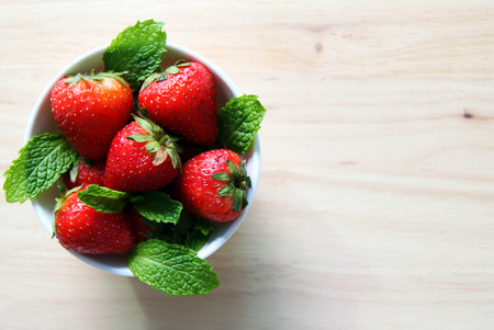 Fresh strawberry with leaves of mint on the wooden background.の写真素材