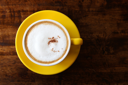 Travel to Chiangmai, Thailand. Cappuccino in the yellow cup on the wooden background.の写真素材