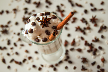 A glass of ice cream with coffee decorated of cinnamon sticks, coffee beans and star of anise on the white background.の写真素材