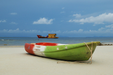 Travel to island Phi Phi, Thailand. The green-red-white boat on the sand beach with sea and blue sky on background.の写真素材