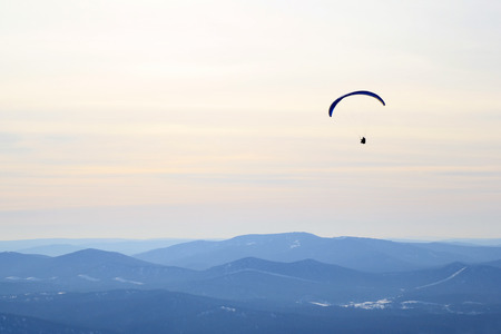 Travel to Sheregesh, Russia. Paraglider is flying in the sky above the mountains. Winter landscape.の写真素材