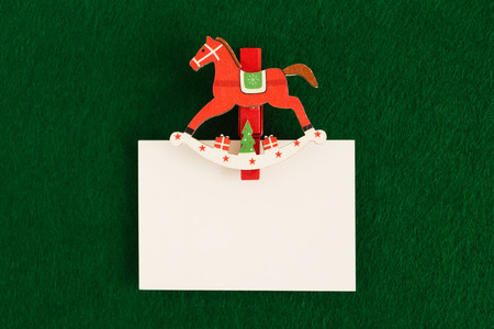White sheet with red and white wooden pin on the green background for Christmas greetings. Copy space.の写真素材