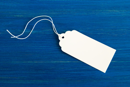 White blank paper price tag or label set on the blue wooden background, top view.の写真素材
