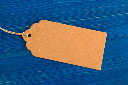 Brown blank paper price tag or label set on the blue wooden background, closeup.の写真素材