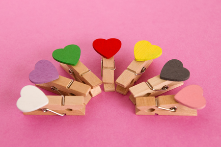 Wooden pins with colorful hearts on the pink background. Decorations for Valentine Day.の写真素材