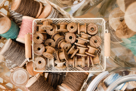 Top view on small wooden coils in a basket and big coils with colorful threads.の写真素材