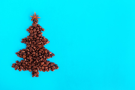 Christmas tree made from coffee beans and decorated anise star on a blue background, top view.の写真素材