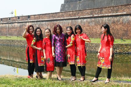 Hue, Vietnam - February 10, 2018: Group of Vietnamese women in the traditional dresses on a background of wall of Hue Imperial City before celebration of Tet - Vietnamese New Year.のeditorial素材