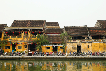 Hoi An, Vietnam - February 12, 2018: The embankment of Thu Bon River with yellow buildings and traditional wooden boats. The historic old town of Hoi An is UNESCO World Heritage Site.のeditorial素材