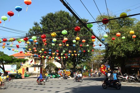 Hoi An, Vietnam - February 15, 2018: View on a busy crossroad in a center of city with motorcyclists, bicyclists, Festive colorful decorations for celebrating Tet - Vietnamese New Year.のeditorial素材