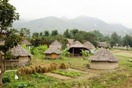 View on wooden houses and garden on a background of mountains in cloudy weather. Pai, Mae Hong Soon...