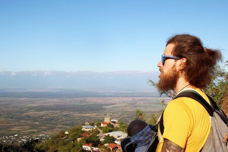 Father is travelling in the mountains with his little daughter in ergo carrier.