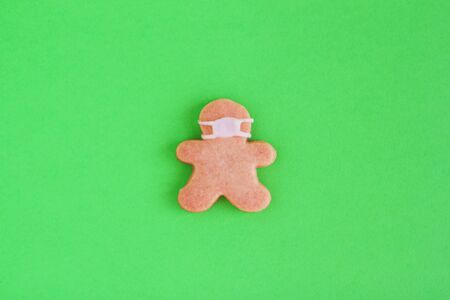 Homemade cookies in shapes of man with medical mask on green background, top view. Sweet shortbread...