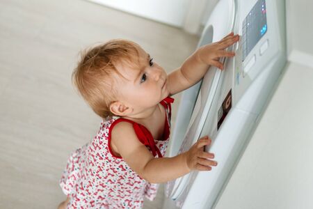 Child with washing machine. Little girl is helping with family chores.の写真素材