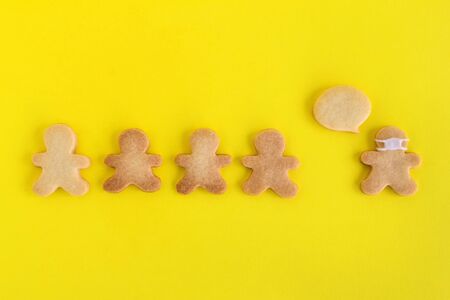 Homemade shortbread cookies with white glaze on yellow background, top view. Crowd of people and one...