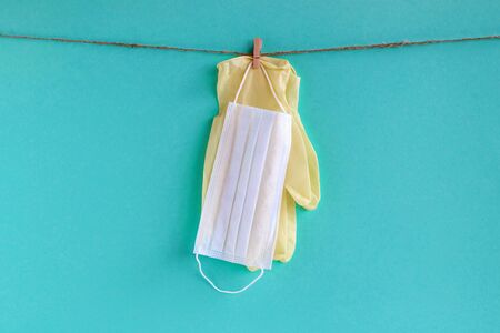 Drying of medical face masks and disposable gloves after washing on a rope for reuse, on a turquoise background with copy space. Concept of new normal lifestyle.の写真素材