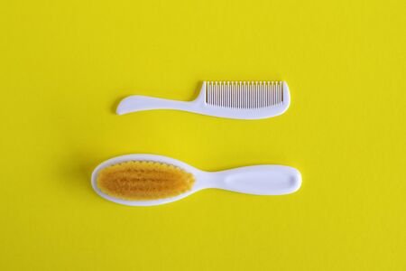 White hairbrush and comb for baby on white background, flat lay with copy space. Baby care concept.