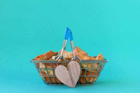 Shopping basket with traditional Italian almond cookies cantucci decorated wooden heart on blue background. Concept for Valentine's Day.の写真素材