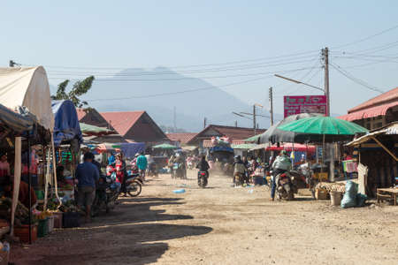 Luang Prabang, Laos - January 23, 2018: Authentic local street market with food, fruits, vegetables and other things. Lifestyle photo of people on motorbikes who are buying the necessary goods.のeditorial素材