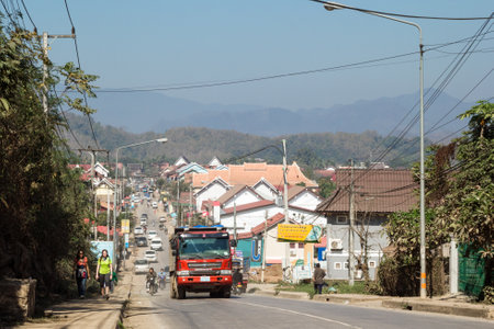 Luang Prabang, Laos - January 23, 2018: View on busy street with different transport, residential...