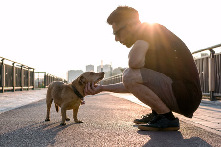 Young handsome man is walking with his dog in the morning on empty street of city.の写真素材