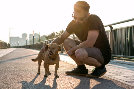 Young handsome man is walking with his dog in the morning on empty street of city.の写真素材