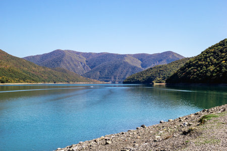 Scenic view on bank of lake with blue water and mountains in sunny weather. Caucasus Mountains, Georgia.の写真素材