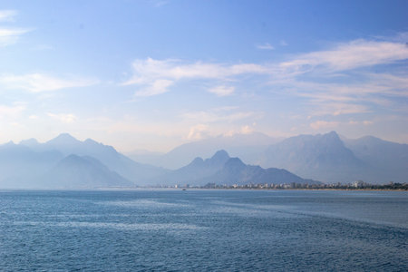 Tranquil seascape with distant mountain range, clear blue sky, and serene atmosphereの写真素材