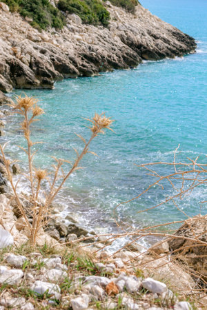A picturesque rocky beach in the Mediterranean Sea with clear blue water and stones. The beach is in a cove surrounded by cliffs. Crystal clear water allows you to see the stones on the seabed.の写真素材