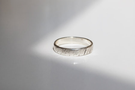 Minimalist silver ring with brushed texture on white background, elegant jewelry for women and men.
